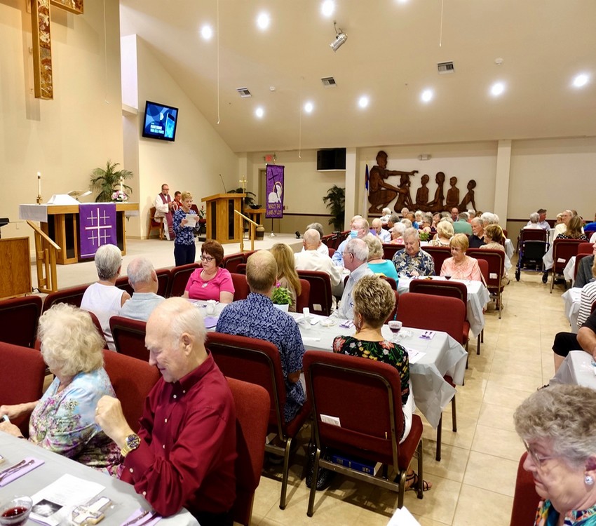 Photo of gathering in Santuary with people sitting at tables